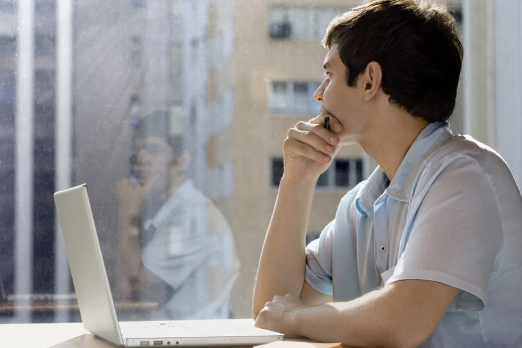 Businessman with laptop looking out window